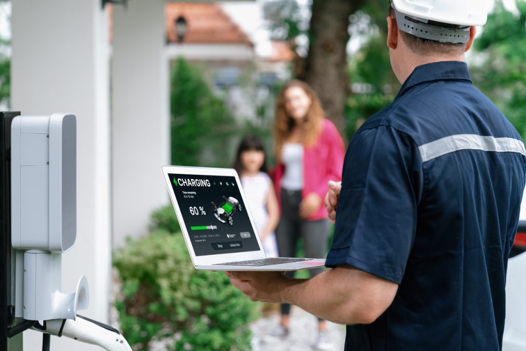 multifamily ai tools Technician in uniform and helmet checks a charging station with a laptop. Charging status shows 60%. Two people stand in the background. mpro Digital Edge