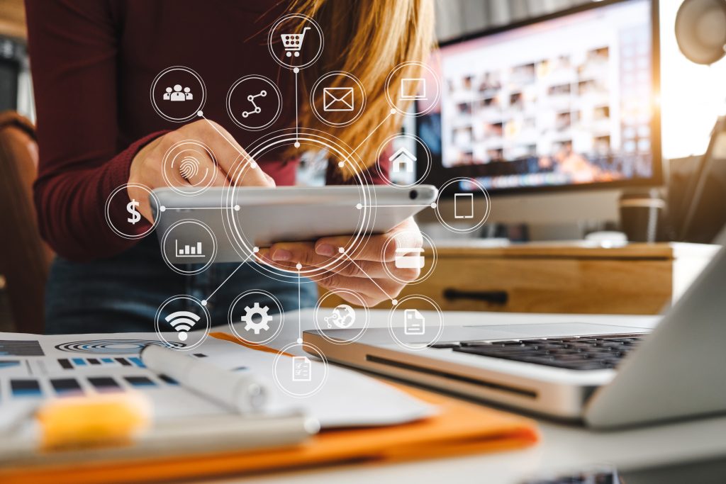 multifamily ai tools Person using a tablet at a desk with various technology and social media icons overlaid. A laptop and documents are nearby, and a computer screen is visible in the background. mpro Digital Edge