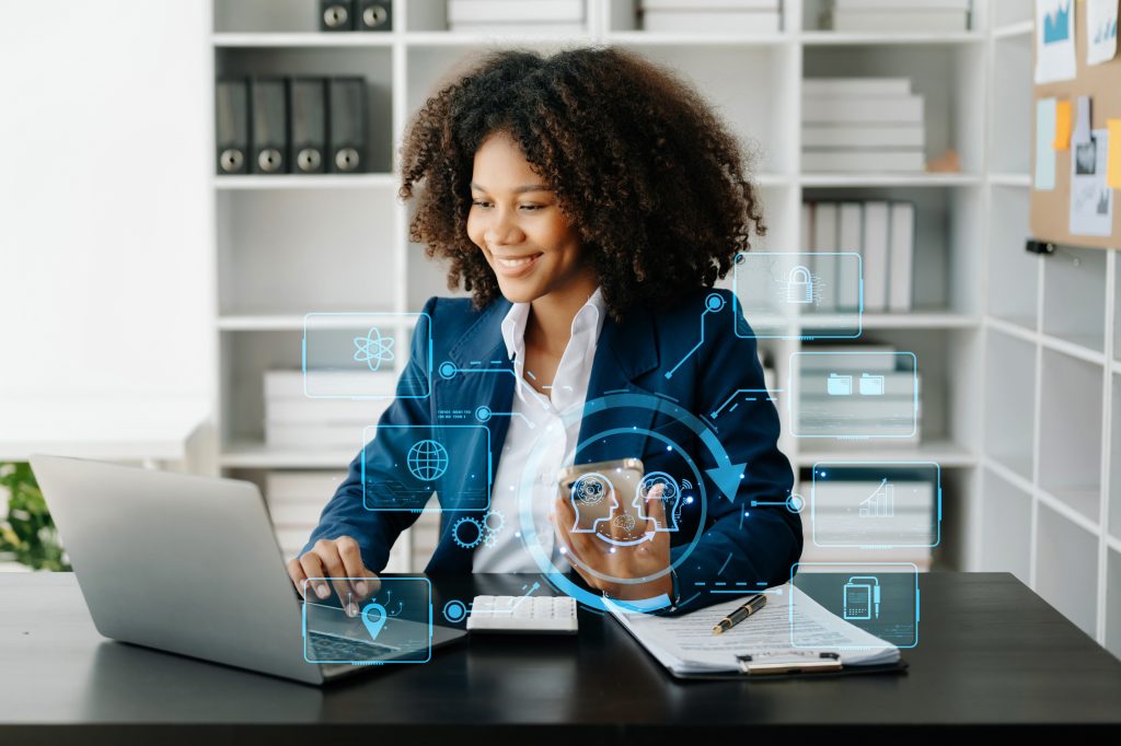 multifamily ai tools A woman in a suit works on a laptop at a desk, surrounded by digital icons and holograms. Bookshelves can be seen in the background. mpro Digital Edge