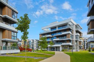 multifamily ai tools Modern apartment buildings with large windows and balconies, surrounded by a well-maintained lawn and young trees, under a partly cloudy blue sky. mpro Digital Edge