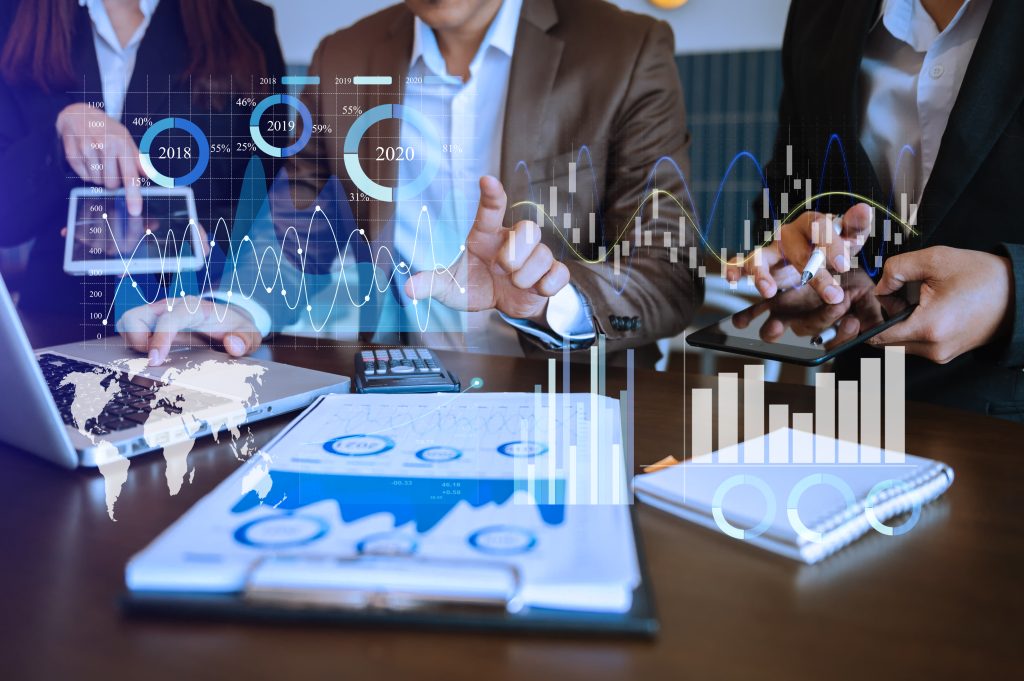 multifamily ai tools Business professionals analyzing graphs and data visuals on paper and electronic devices, with overlay of digital charts and timelines from 2018 to 2020. mpro Digital Edge